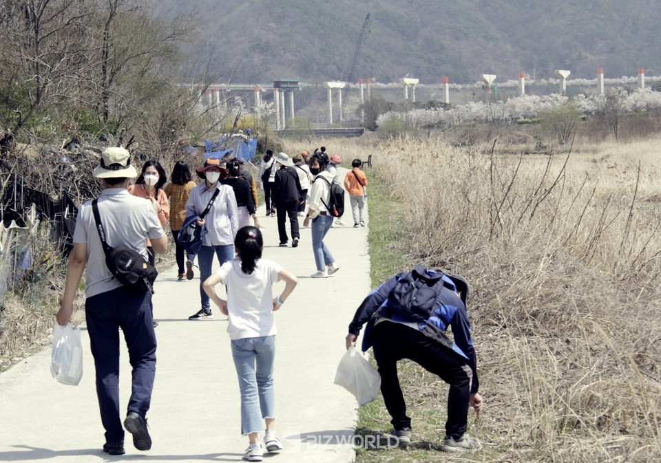 어슬렁 투어 참가자가 산책길 주변에 버려진 쓰레기를 줍고 있다. 사진=손진석 기자