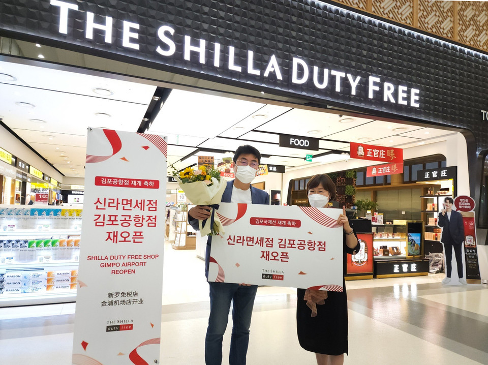 장애리 신라면세점 김포공항점장(오른쪽)이 재오픈 첫 구매 고객에게 꽃다발과 기념품을 선물로 증정하고 기념 촬영을 하고 있다. 사진=호텔신라
