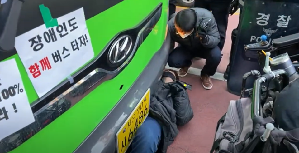 전장연 소속 장애인이 버스 밑에 들어가 버스운행을 방해하고 있다. 사진=김종길 시의원