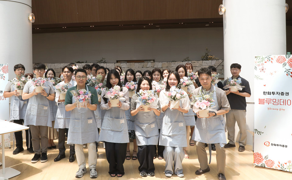 한화투자증권 임직원들이 지난 18일 서울시 영등포구 본사에서 직접 제작한 플라워 박스를 들고 기념촬영을 하고 있다. 사진=한화투자증권