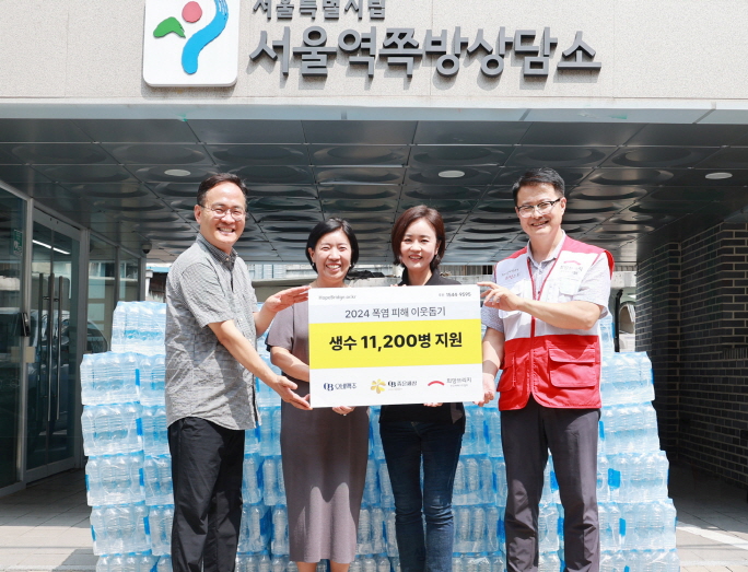 9일 오비맥주가 후원한 재난취약계층 폭염 대응 생수 전달식에 참석한 관계자들이 기념촬영을 하고 있다. 사진=희망브리지