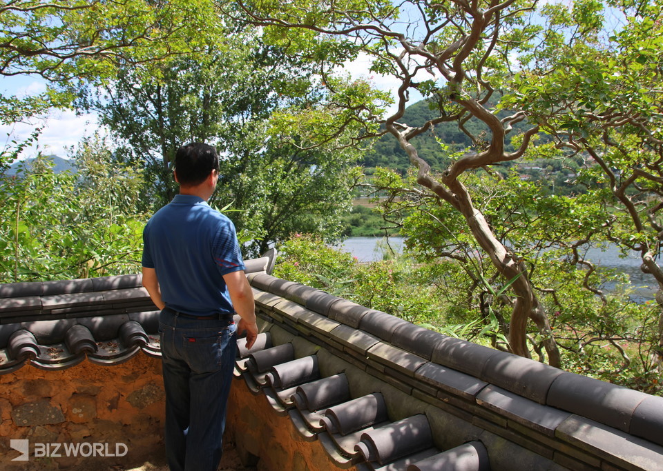 월영정 담 너머로 보이는 밀양강을 바라보며 잠시 시간을 보내고 있는 관람객. 사진=손진석 기자