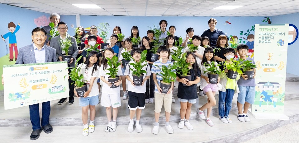 현대백화점 임직원들이 정부 탄소중립 프로그램 '기후행동 1.5℃ 스쿨챌린지'에서 금상을 받은 경기도 파주 운정초등학교를 방문해 공기정화식물을 전달하고 학생 및 선생님들과 기념촬영을 하고 있다. 사진=현대백화점