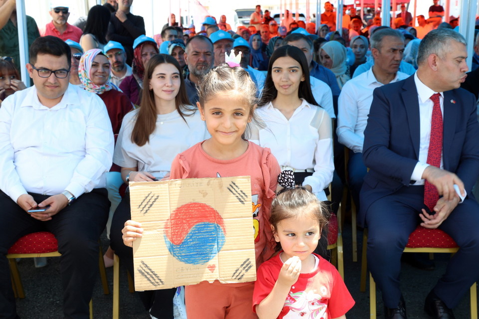 튀르키예 임시주거시설에 거주 중인 지진 피해 아동이 손수 그린 태극기를 들고 사진을 찍고 있다. 사진=희망브리지