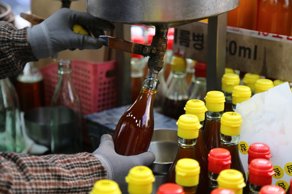 모란민속시장에서 판매하고 있는 갓 짠 참기름을 담는 모습. 사진=길지혜 작가