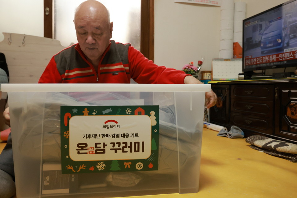 희망브리지 한파·감염 대응세트를 전달받고 확인하고 있다. 사진=희망브리지