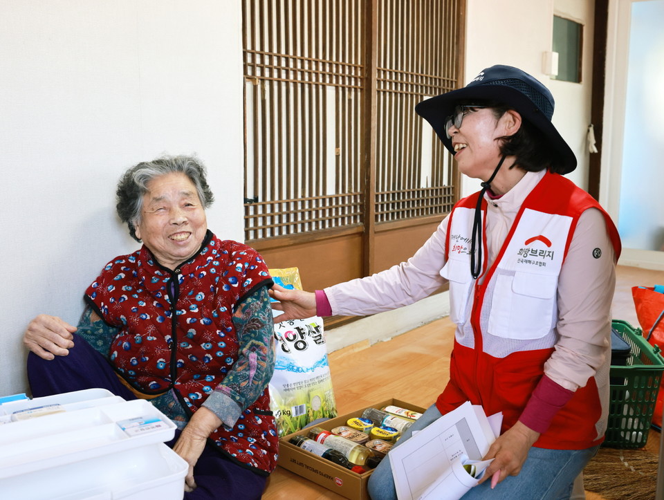희망브리지 자원봉사자가 경기 광주시 재난피해세대를 찾아 희망이음사업 지원 물품을 전달하고 안부를 나누고 있다. 사진=희망브리지