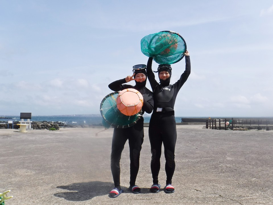 태왁과 망사리를 들고 기념 사진을 남기는 관광객. 사진=한국관광공사