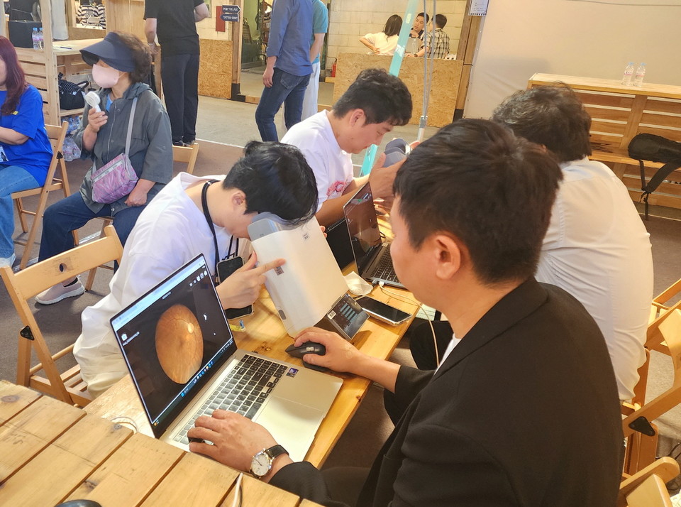 대웅제약 부스 방문객이 위스키와 옵티나를 활용해 안저 상태를 확인하고 있다. 사진=대웅제약