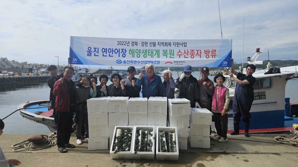 울진 연안어장 해양생태계 복원 수산종자 방류에 참여한 어촌계 주민들이 방류 전 전복 종자를 앞에 두고 기념촬영을 하고 있다. 사진=희망브리지