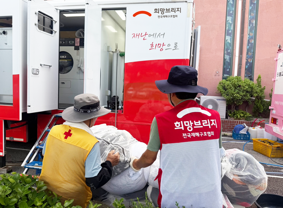 희망브리지 봉사자와 유관기관 봉사자가 세탁차량 앞에서 수해 이웃의 세탁물을 정리하고 있다. 사진=희망브리지